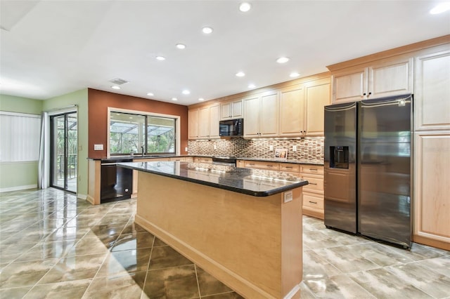 kitchen featuring light brown cabinets, a center island, dark stone counters, black appliances, and tasteful backsplash