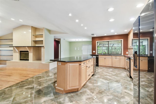 kitchen with stainless steel electric range oven, dark stone countertops, a center island, light brown cabinetry, and a sink