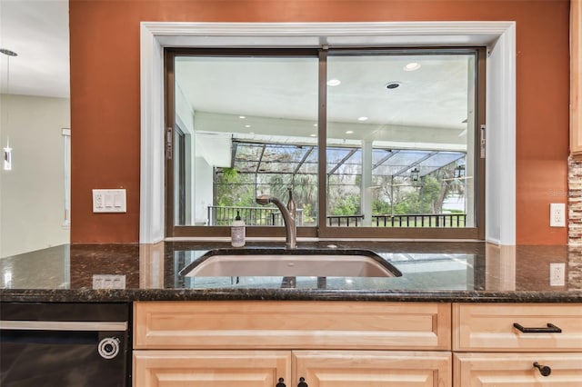 kitchen featuring dishwasher, light brown cabinets, a sink, and dark stone countertops