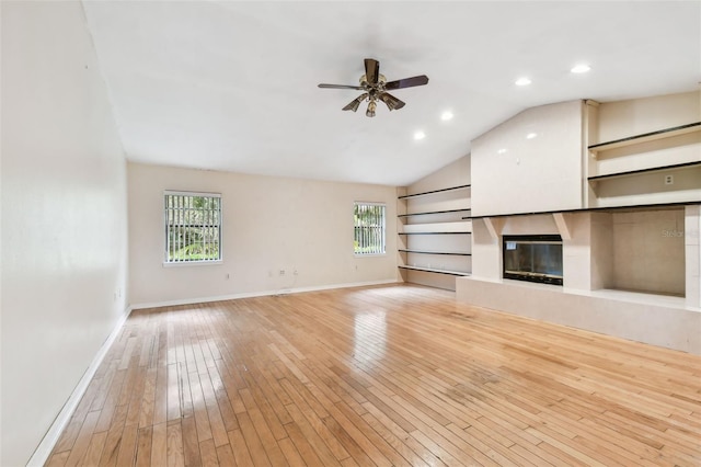 unfurnished living room featuring built in features, a fireplace, lofted ceiling, light wood-type flooring, and baseboards