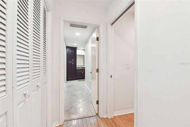 hallway featuring recessed lighting, baseboards, and light wood finished floors