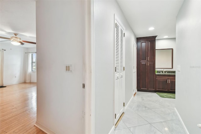 hallway with recessed lighting, a sink, and baseboards