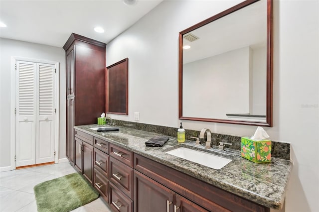 full bathroom featuring double vanity, visible vents, a sink, tile patterned flooring, and a closet