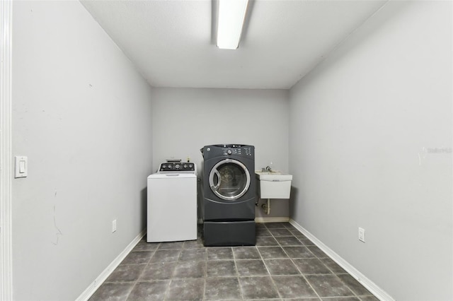 laundry room featuring laundry area, a sink, baseboards, and separate washer and dryer