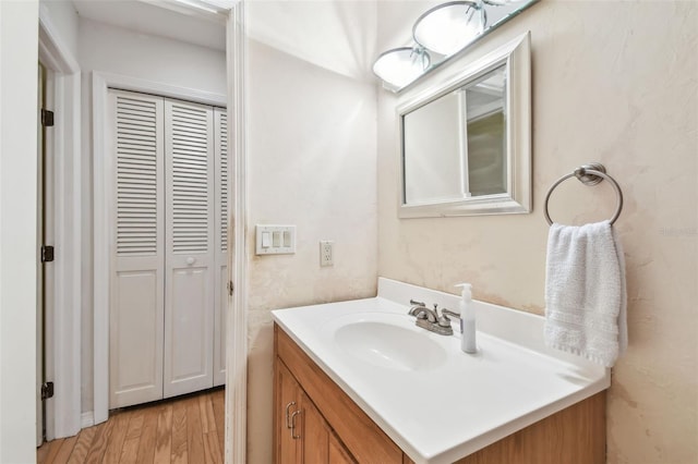 bathroom with a closet, wood finished floors, and vanity