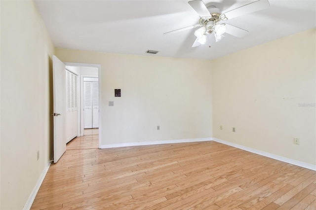 empty room featuring light wood-type flooring, visible vents, and baseboards