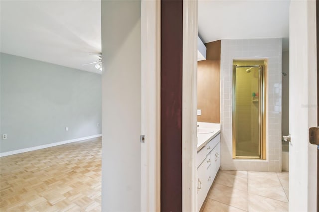 bathroom with a ceiling fan, a stall shower, vanity, and baseboards