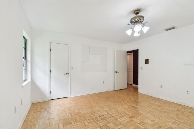 spare room with ceiling fan, visible vents, and baseboards