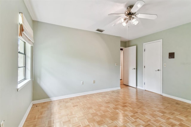 empty room featuring ceiling fan, visible vents, and baseboards