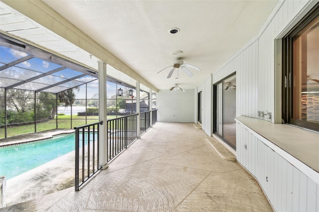 outdoor pool with glass enclosure, a patio area, and a ceiling fan