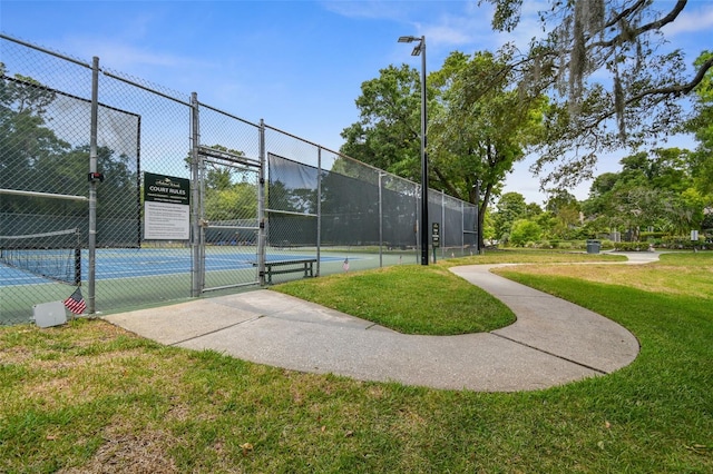 view of sport court featuring a gate, fence, and a lawn