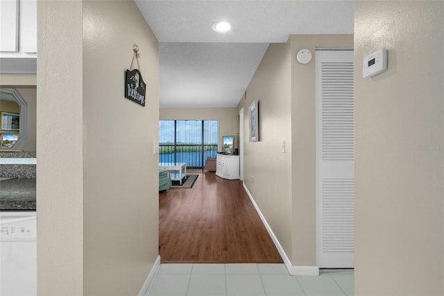 hall featuring light tile patterned flooring and baseboards