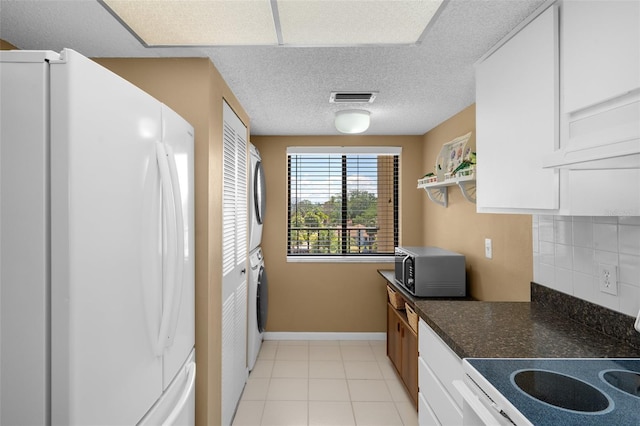 kitchen with white appliances, white cabinets, stacked washer and clothes dryer, dark countertops, and backsplash