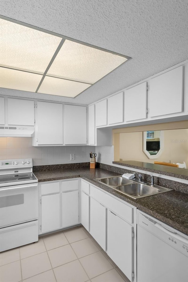 kitchen featuring under cabinet range hood, white appliances, a sink, white cabinetry, and dark countertops