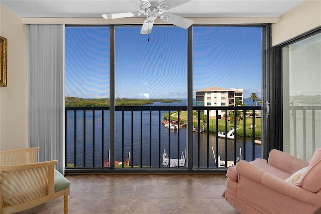 sunroom / solarium with a ceiling fan and a water view