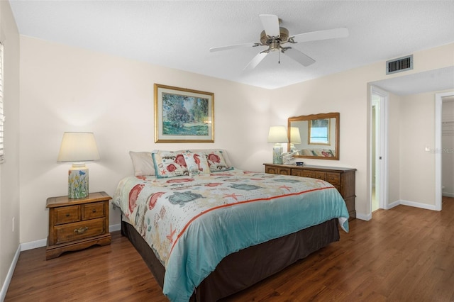 bedroom with baseboards, visible vents, dark wood finished floors, ceiling fan, and a textured ceiling