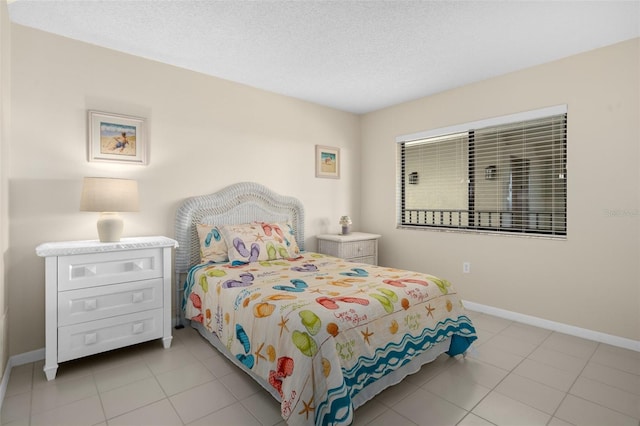 bedroom featuring a textured ceiling, light tile patterned flooring, and baseboards