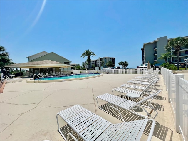 pool with a patio area and fence