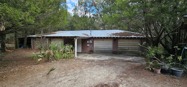 ranch-style house with metal roof, an attached garage, and driveway