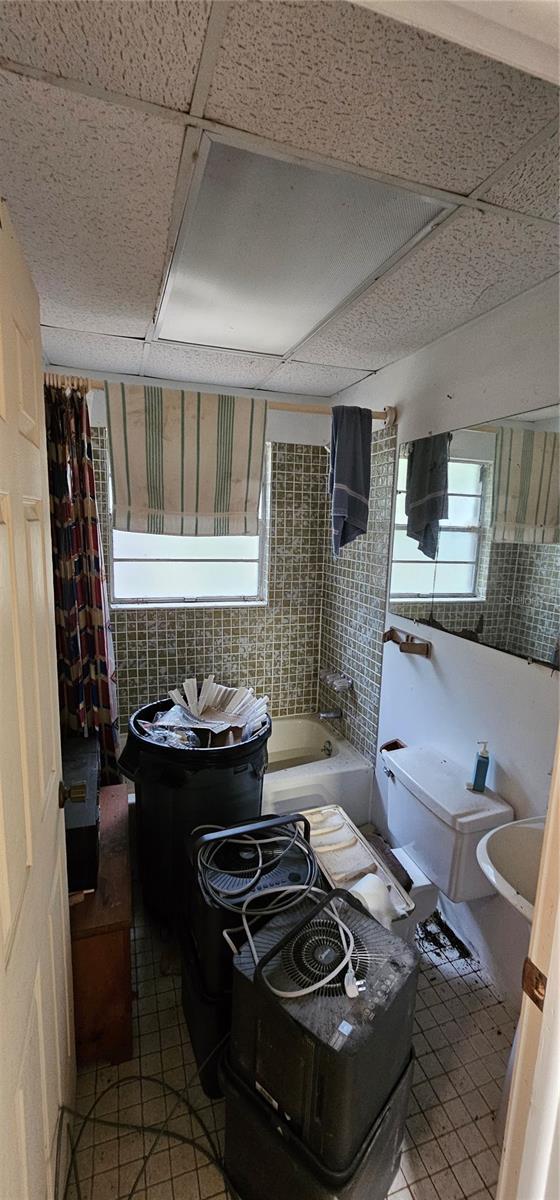 full bath with a drop ceiling and tile patterned flooring