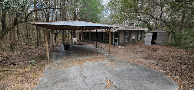 exterior space with driveway, a carport, and a shed