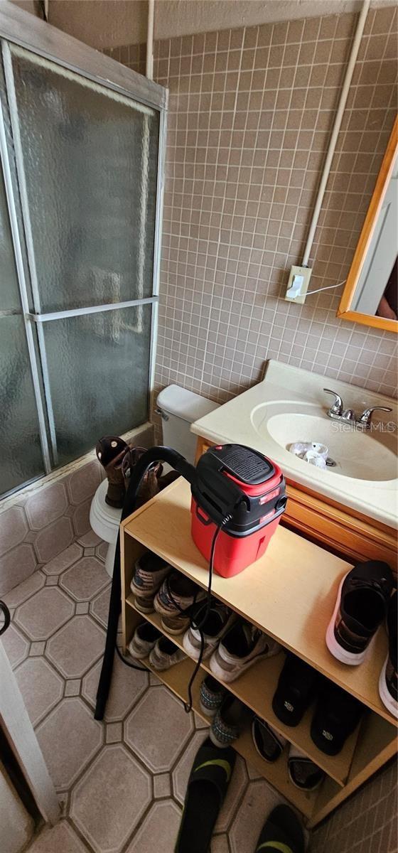 11617 Duda Rd, Hudson, FL 34667 - bathroom with enclosed tub / shower combo, vanity, tile walls, backsplash, and tile patterned floors