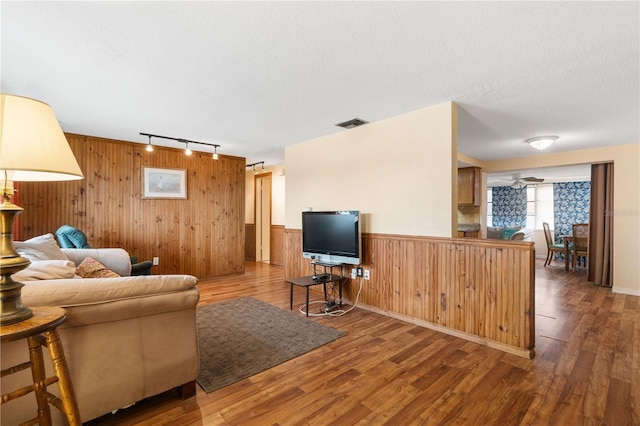 living area with a textured ceiling, wood finished floors, and wainscoting