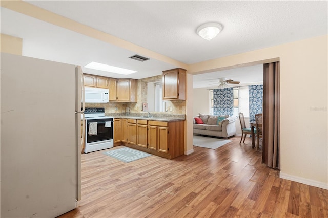 kitchen with white appliances, light wood finished floors, visible vents, light countertops, and backsplash