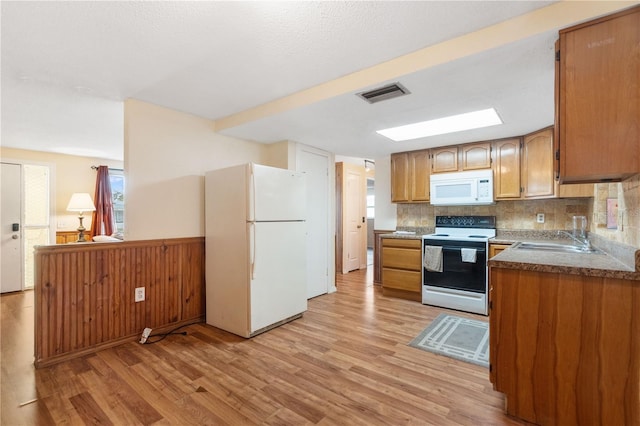 kitchen with white appliances, light wood-type flooring, a sink, and visible vents