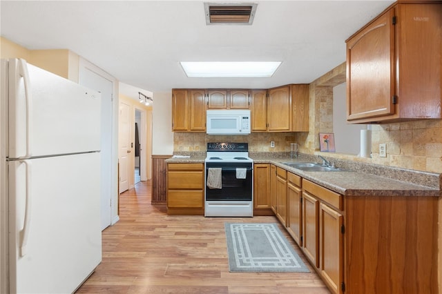 kitchen with visible vents, decorative backsplash, a sink, light wood-type flooring, and white appliances