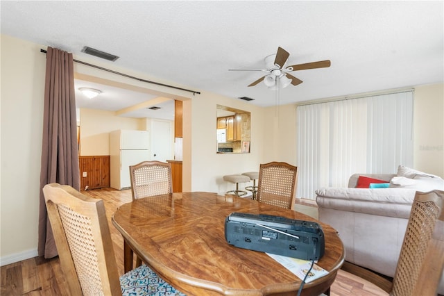 dining room with a textured ceiling, light wood-type flooring, visible vents, and a ceiling fan