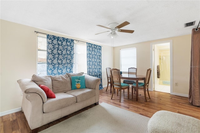 living room featuring a wealth of natural light, a textured ceiling, visible vents, and wood finished floors