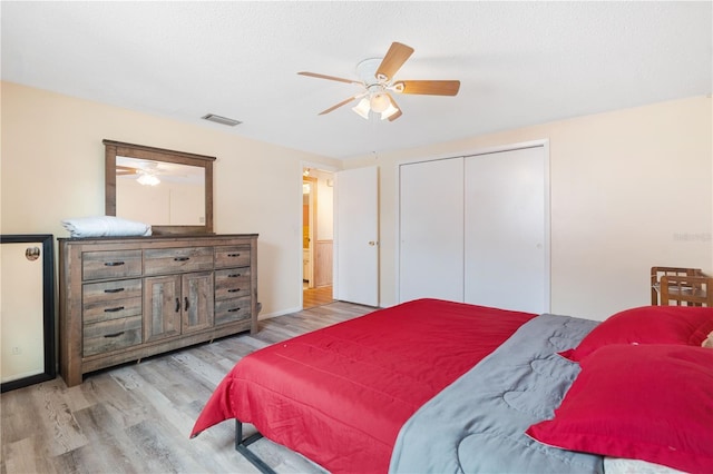 bedroom with baseboards, visible vents, ceiling fan, wood finished floors, and a closet