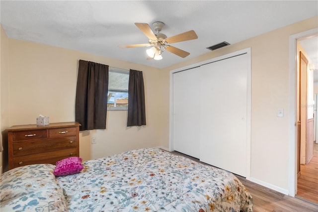 bedroom featuring baseboards, visible vents, a ceiling fan, wood finished floors, and a closet