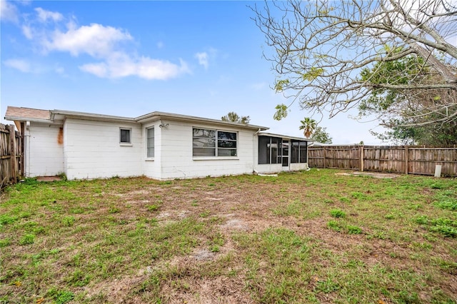 rear view of house featuring a sunroom, a fenced backyard, and a yard