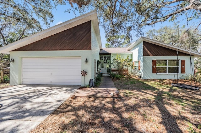 view of front of home featuring driveway, a garage, and stucco siding