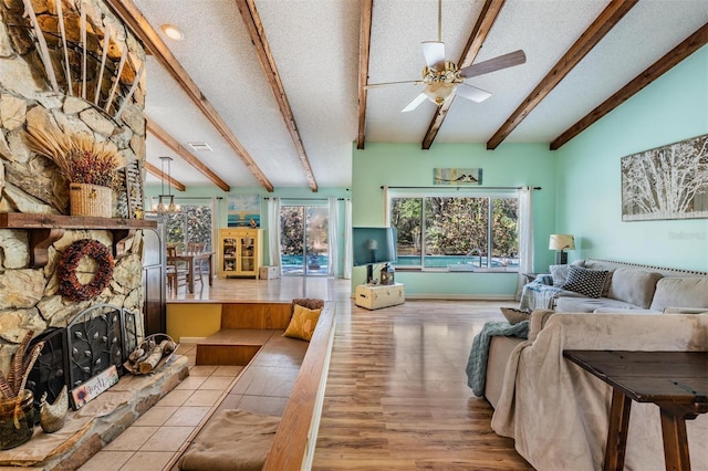 living area featuring lofted ceiling with beams, a textured ceiling, a fireplace, and a wealth of natural light