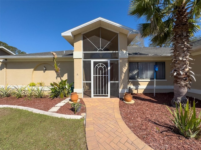 entrance to property featuring a shingled roof and stucco siding