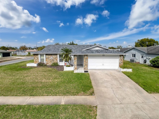 ranch-style home featuring an attached garage, central air condition unit, stone siding, driveway, and a front yard