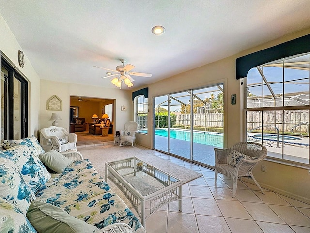 living area featuring light tile patterned floors, ceiling fan, baseboards, and a sunroom