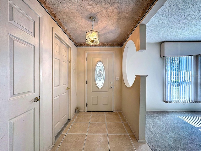 entrance foyer featuring light tile patterned floors, baseboards, a textured ceiling, and light colored carpet