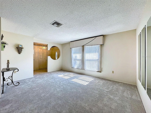 carpeted spare room with visible vents and a textured ceiling