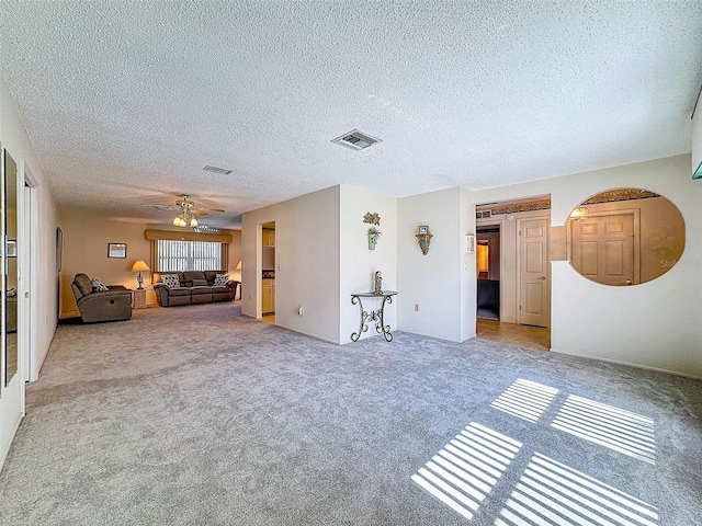 unfurnished living room featuring carpet flooring, ceiling fan, visible vents, and a textured ceiling