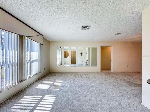 spare room with a textured ceiling, carpet flooring, and visible vents