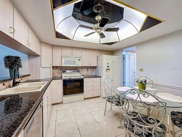 kitchen featuring light tile patterned flooring, white appliances, a sink, decorative backsplash, and dark countertops