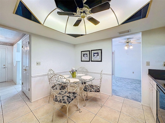 dining area featuring ceiling fan, visible vents, light colored carpet, and light tile patterned flooring