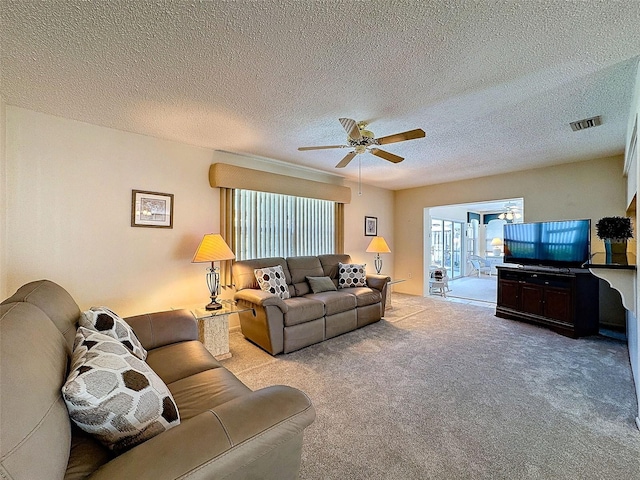 living area with a textured ceiling, carpet floors, visible vents, and a ceiling fan