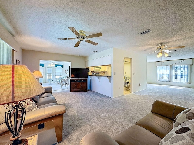 living area with light carpet, a wealth of natural light, and visible vents