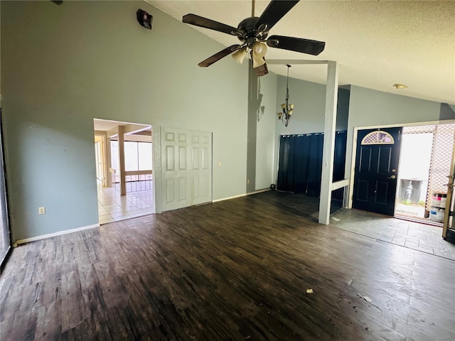 unfurnished living room with ceiling fan with notable chandelier, a textured ceiling, baseboards, and wood finished floors