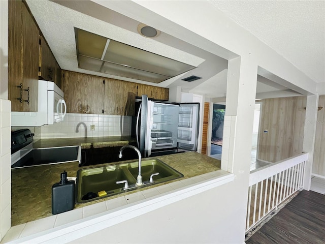 kitchen featuring electric stove, tile countertops, visible vents, backsplash, and a sink